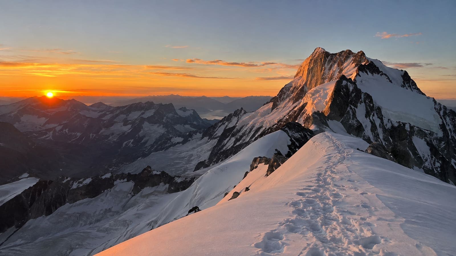 Trace sur une arête sommitale enneigée, sommet éclairé par le soleil rasant